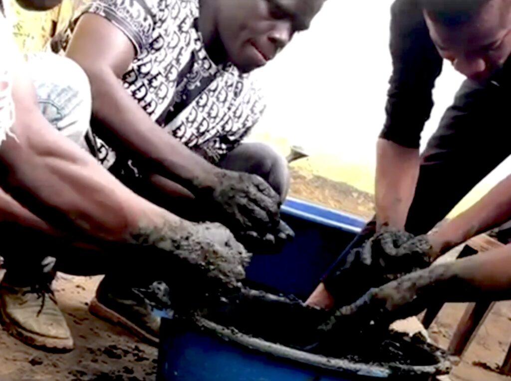 A group of young people learn how to make bricks. Here they are doing mud work.